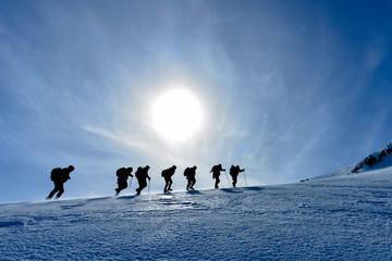 climbers march towards the summit on a windy winter day