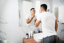 Smiling Young Man Touching His Chin Before Mirror