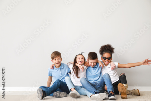 Fotomural Happy children in jeans sitting near light wall