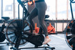 © Viacheslav Yakobchuk - Woman wearing grey leggings and white sneakers cycling in gym