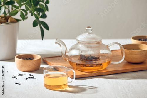 Cuadros en Lienzo Tea in a transparent cup and teapot on a wooden background