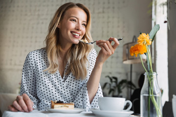 Wall Mural - Beautiful young blonde woman sitting at the cafe