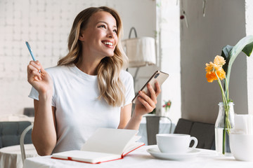 Poster - Beautiful young blonde woman sitting at the cafe