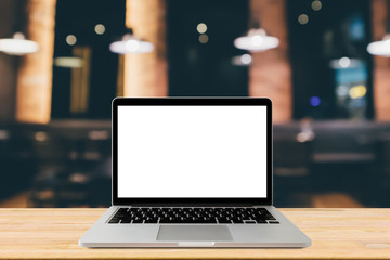 Blank screen laptop computer on wood table top with blur cafe restaurant with abstract bokeh light defocused background