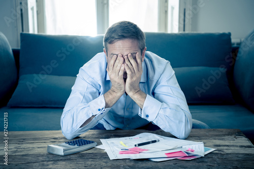 Fotomural Upset man in stress paying bills counting finance with calculator bank papers ex