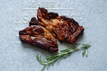 Poster - Cooked black angus prime beef steak with rosemary and olive oil shot on metallic tray