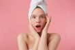 © timtimphoto - Close up of young amazed woman after shower with a towel on her head, looks at the camera with wide open mouth and eyes, touches face, stands over pink background.