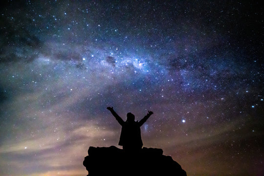 silhouetted person hails the cosmos milky way starry night sky