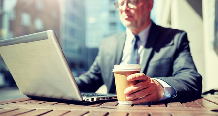 Poster - business, hot drinks, technology and people and concept - senior businessman with laptop computer drinking coffee from paper cup outdoors