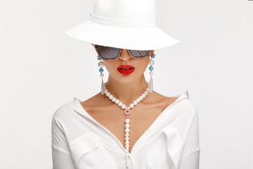 Beautiful girl in an elegant white hat, sunglassess and exquisite jewelry.