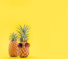 Wall Mural - Creative pineapples with sunglasses isolated on yellow background, summer vacation beach idea design pattern, copy space, close up, blank for text