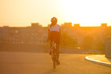 Fototapeta  - Young Woman Riding Road Bicycle on Free Street in the City at Sunset. Healthy Lifestyle and Sport Concept.
