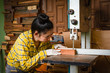 © Thicha - Women standing is craft working cut wood at a work bench with band saws power tools at carpenter machine in the workshop