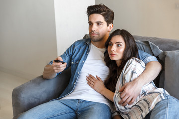 Wall Mural - Attractive young couple relaxing on a couch at home