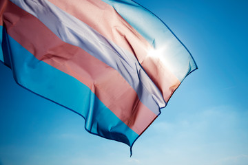 transgender pride flag waving on the blue sky