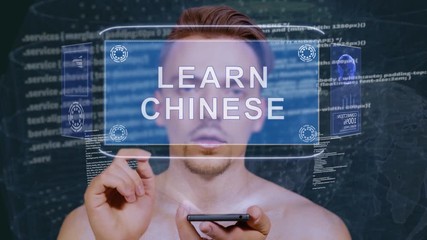 Young man interacts with a conceptual HUD hologram with text Learn Chinese. Guy with future technology mobile screen on background of the program code