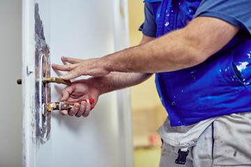 Wall Mural - Handyman using chisel around doors lock tto scrub the old paint.