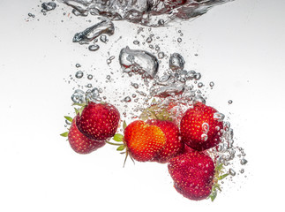 Wall Mural - Close-up photo, on a very short exposure, strawberries falling into the water on a white background close up