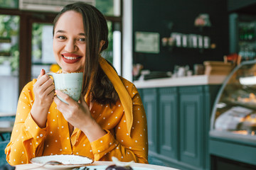 Happy beautiful plus size woman smiling and drinking coffee in cafe