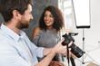 © Drobot Dean - Portrait of handsome photographer man shooting lovely african american female model in studio
