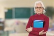 © BillionPhotos.com - Mature woman teacher with books on background