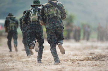 backside of soldiers running forward in the battle beach 