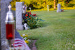 Headstone and American flag alone in a cemetery with green grass and long shadows.