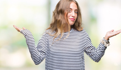 Poster - Beautiful young blonde woman wearing stripes sweater over isolated background clueless and confused expression with arms and hands raised. Doubt concept.