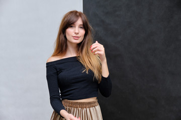 Beauty portrait of a beautiful pretty brunette girl in a black sweater on a two-color background. A woman is happy with life, stands in front of the camera, smiles. Made in a studio.