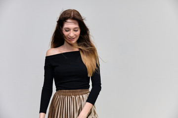 Photo portrait of a beautiful pretty brunette girl in a black sweater on a gray background. A woman is satisfied with her life, she stands in front of the camera, smiling and talking. Made in studio.