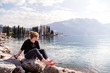 © Tandem Stock - Riva del Garda, Trento, Italy: A woman sitting by the lake and enjoying the warmth of the spring sun.
