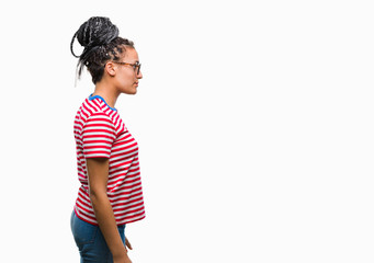 Wall Mural - Young braided hair african american girl wearing glasses over isolated background looking to side, relax profile pose with natural face with confident smile.