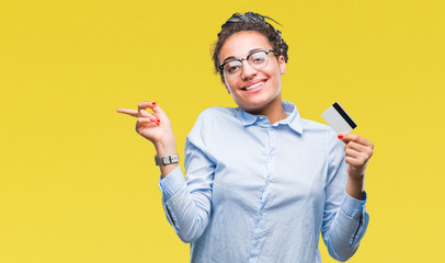 Sticker - Young african american girl holding credit card over isolated background very happy pointing with hand and finger to the side