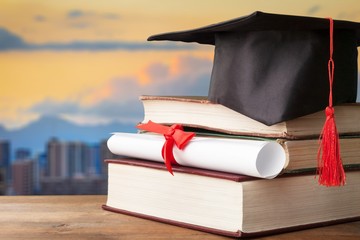 Wall Mural - Graduation hat on stack of books and diploma