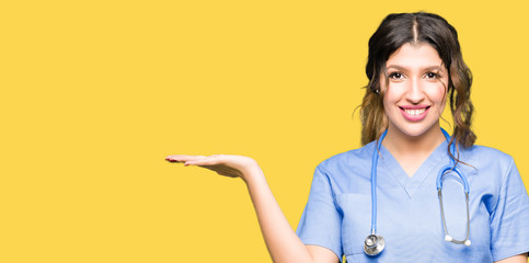 Young adult doctor woman wearing medical uniform smiling cheerful presenting and pointing with palm of hand looking at the camera.