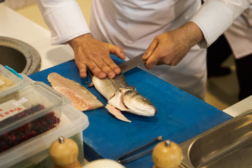 The chef prepares fresh fish fillet. Man hands gutting fish, close-up