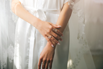 Wall Mural - Bride in white clothes near the window. Beautiful manicure. Elegant nails. Golden rings. Wedding jewellery.