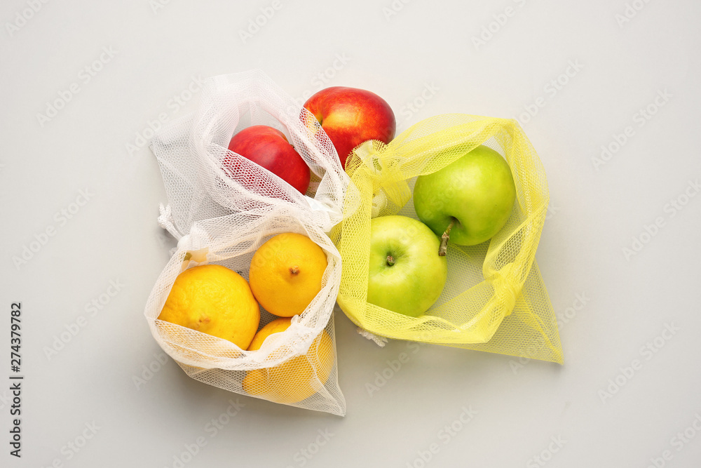 Eco bags with fruits on light background
