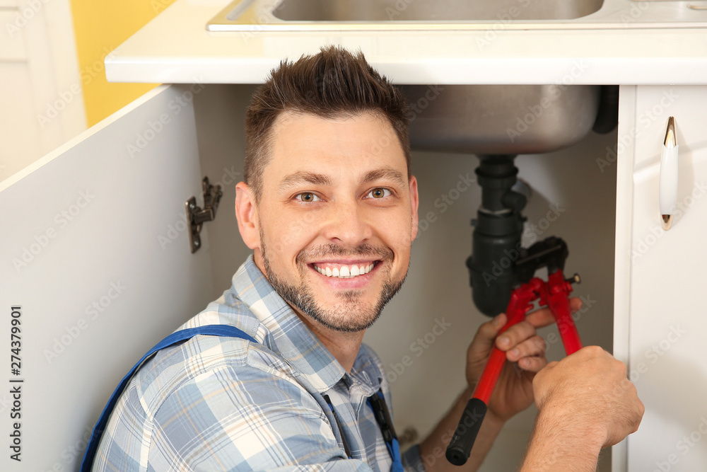 Plumber installing sink in kitchen
