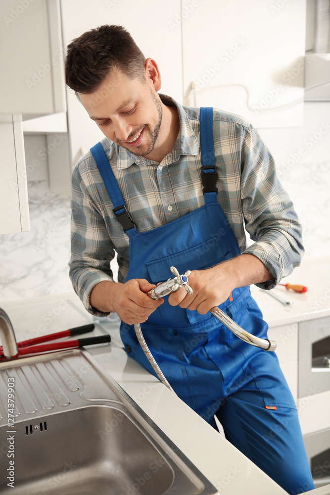 Plumber installing sink in kitchen