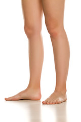 Wall Mural - Side view of female barefoot legs on white background