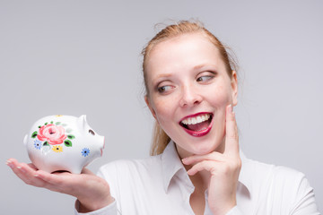 Wall Mural - happy young red haired woman with her piggy bank