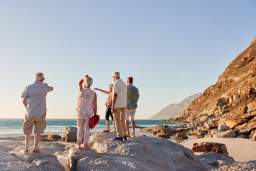 Rear View Of Senior Friends Standing On Rocks On Summer Group Vacation Looking Out To Sea