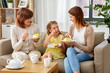 © Syda Productions - family, generation and food concept - smiling mother, daughter and grandmother having tea party and eating cake at home