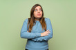 © luismolinero - Young girl over green wall making doubts gesture while lifting the shoulders