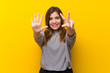 Young girl over yellow wall counting eight with fingers