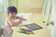 © FAMILY STOCK - Little Asian child using a pencil to write on notebook at the desk