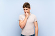 © luismolinero - Handsome young man over isolated blue wall looking to the side