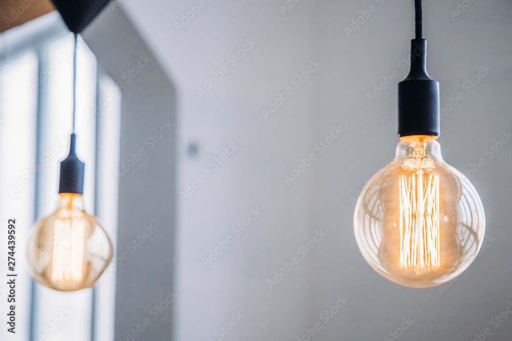 Edison lamp is included in loft room, against background of concrete wall - obrazy, fototapety, plakaty 