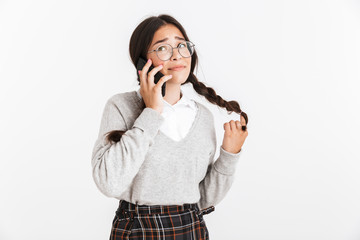 Canvas Print - Photo closeup of pretty teenage girl wearing eyeglasses and school uniform rejoicing while talking on smartphone